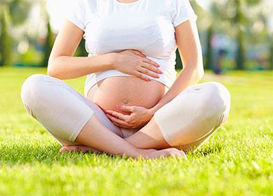 Schwangere Frau, die auf Gras sitzt