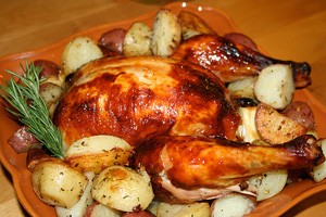 Gebackenes Huhn mit Kartoffeln auf einem Holzbrett