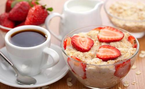 Bezauberndes Frühstück mit Haferflocken, Erdbeeren, Sahne und Kaffee