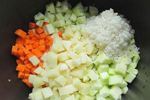 Zucchini und Karotten in Würfel geschnitten und eine Handvoll Reis in einer Mehrkochschüssel