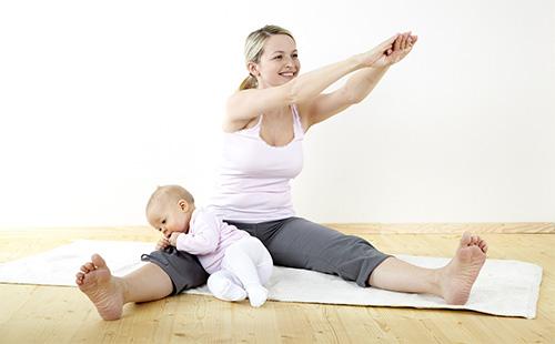 Жена прави упражнения у дома с бебе