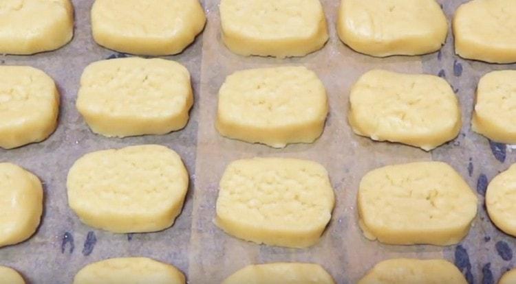 Wir breiten die Kekse auf einem mit Pergament bedeckten Backblech aus und schicken sie in den Ofen.