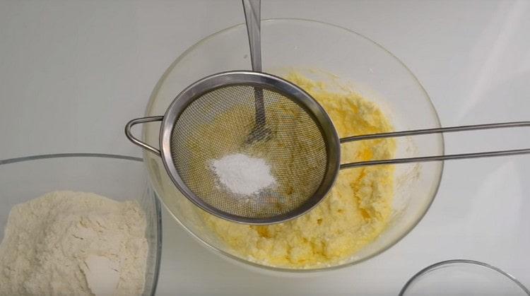 Sinusukat namin ang baking powder sa curd mass sa pamamagitan ng isang salaan.