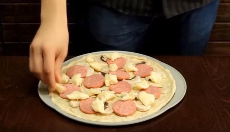 Lubricate ang base para sa pizza na may puting sarsa, kumalat ang pagpuno.