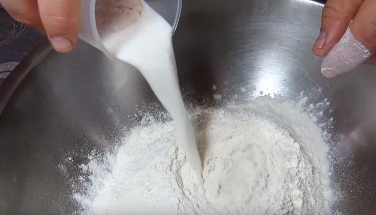Sa sifted flour, ipinakilala namin ang gatas na may lebadura.