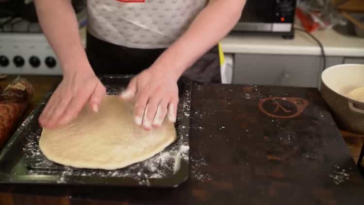 Um eine klassische Pizza zuzubereiten, geben Sie den Teig in eine Form