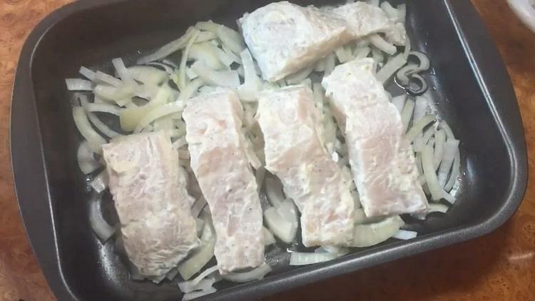 Според рецептата за готвене на щука костур във фурната, сложете лук и риба върху лист за печене