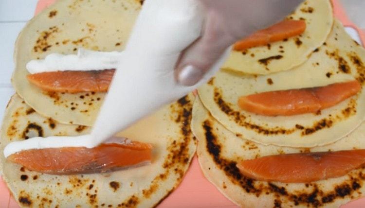 Nagpalaganap kami ng isang piraso ng salmon sa bawat pancake at piniga ang cream cheese malapit dito.