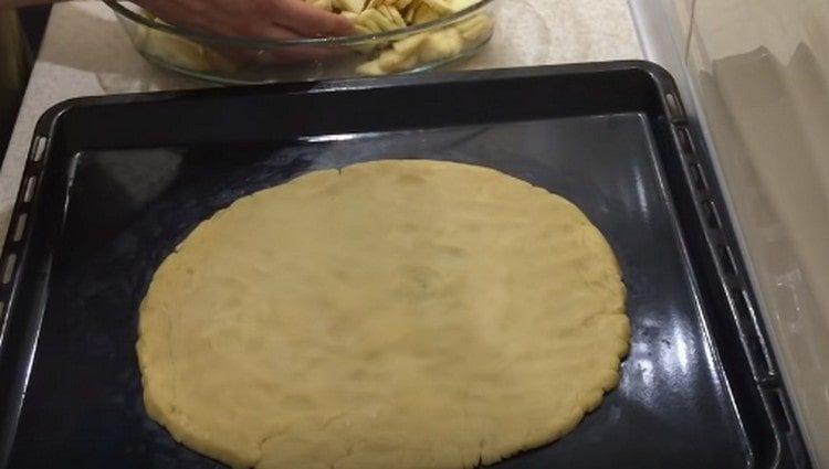 Mula sa masa sa isang baking sheet bumubuo kami ng isang bilog na base para sa pie.