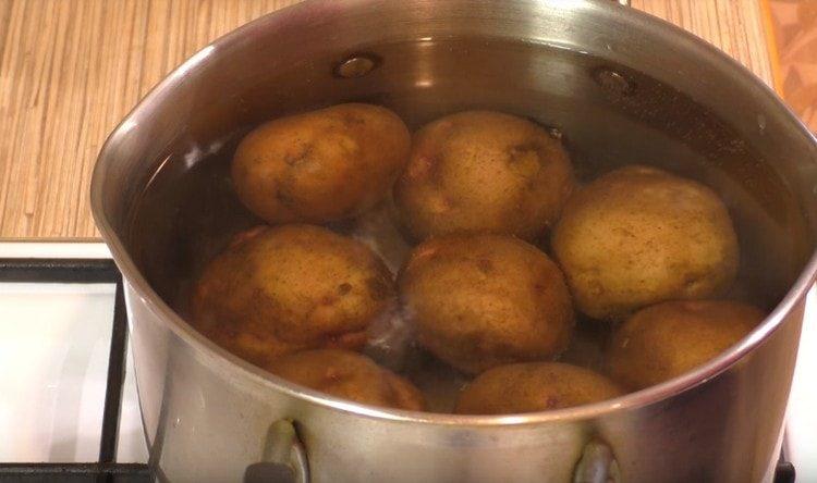 أولا ، غلي البطاطا في سترة جلودهم حتى نصف جاهزة.